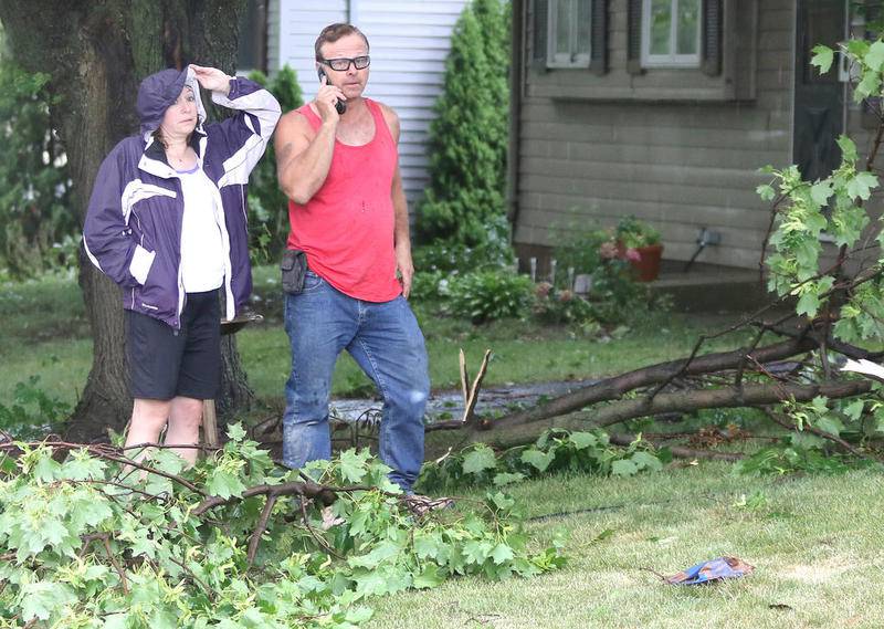Scott Sunleaf talks on the phone as his wife Lane surveys the damage after a tree limb fell on their house on Hadsall Street in Genoa Monday afternoon during a severe storm that passed through the area. High winds, lightning and heavy rain caused damage consisting mainly of downed trees and power lines throughout DeKalb County.