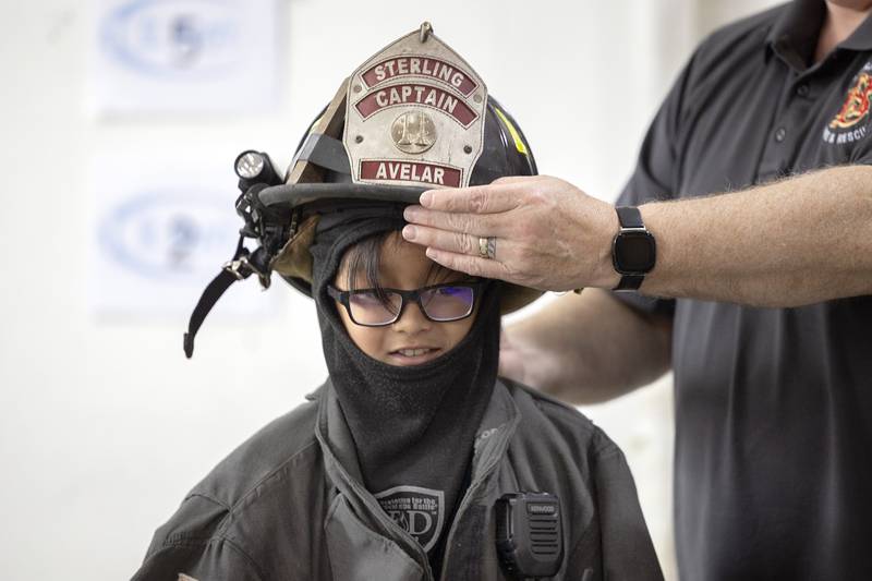 St. Mary’s Sterling 3rd grader Caden Saguilla has a firefighter helmet placed on his head by Sterling Deputy Chief Dave Northcutt Monday, Jan. 29, 2024 in celebration of Catholic Schools Week.
