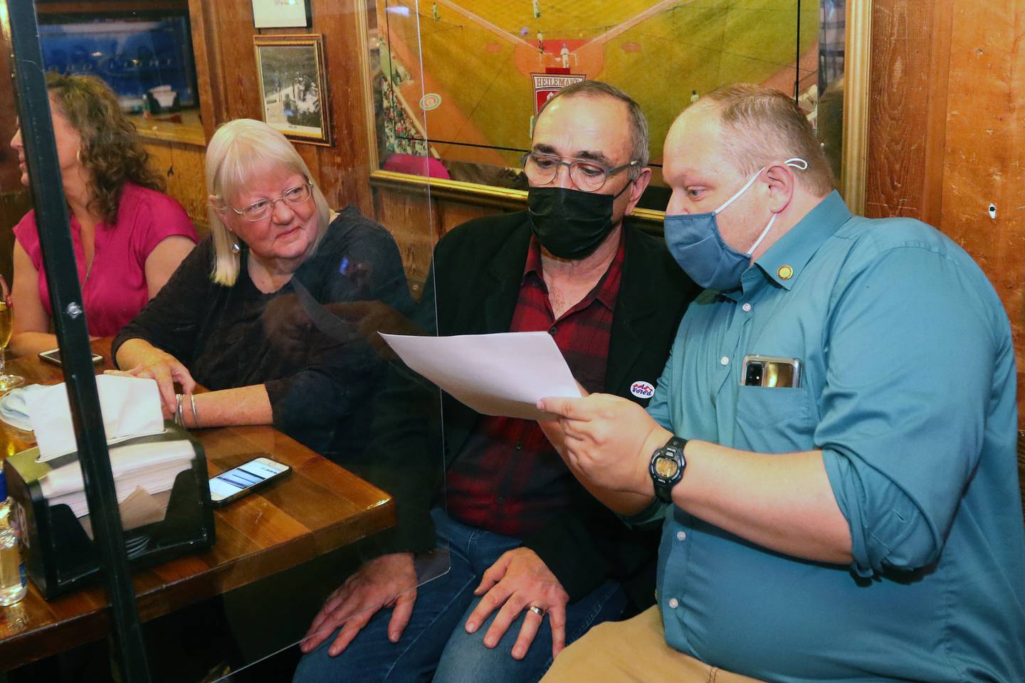 Crystal Lake city clerk Nick Kachiroubas, right, goes over election results with incumbent acting Crystal Lake mayor Haig Haleblian as they watch election results roll in with Carolyn Seegers  and other supporters during an election night watch party at The Cottage on Tuesday, April 6, 2021 in Crystal Lake.