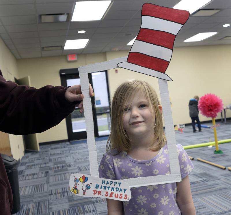 Matilda Sengstock has her photo taken within a "Cat In The Hat" frame Thursday, March 7, 2024, at the Reddick Library in Ottawa during a special Dr. Seuss miniature golf outing to celebrate the author’s March 2 birthday.
