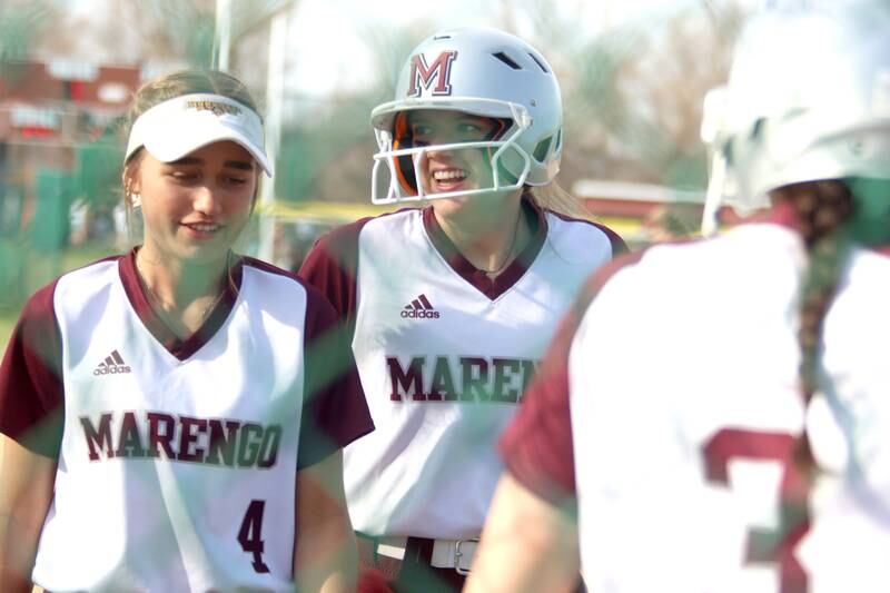 Marengo’s Kylee Jensen, right, is all smiles after belting a home run against Richmond-Burton in varsity softball at Marengo Tuesday. Teammate Maddy Christopher, left, walks with her back to the dugout.