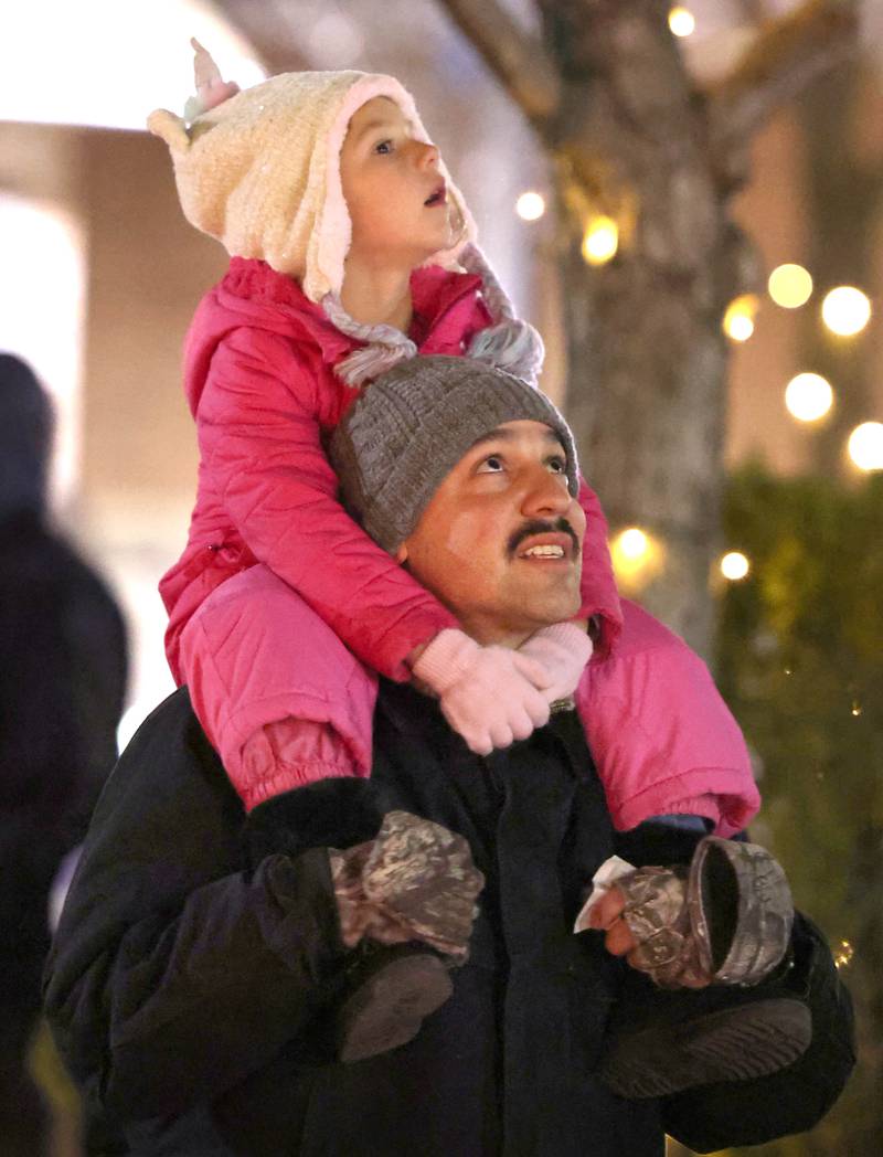 Bryan Phelps and his daughter Mikayla, 5, from Cortland look for Santa’s sleigh in the sky near the Egyptian Theatre Thursday, Dec. 1, 2022, during the DeKalb Chamber of Commerce Lights on Lincoln and Santa Comes to Town.