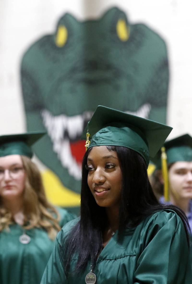 The schools logo looms over Zoe Arcos as she waits Saturday, May 13, 2023, for the graduation ceremony for class of 2023 to begin at Crystal Lake South High School in Crystal Lake.