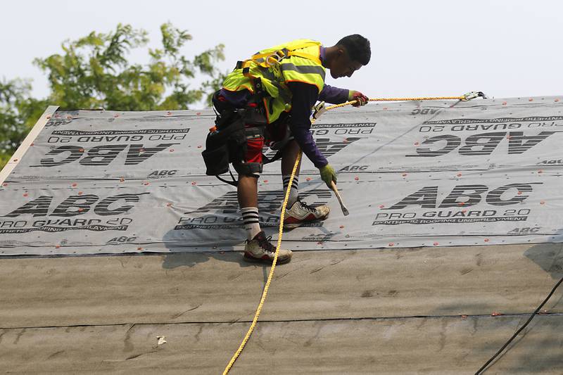 A worker from Apex General Contracting work on installing a new roof Thursday, June 15, 2023, at the home of U.S. Army veteran George Kanaly in Marengo. The Vietnam veteran’s new roof is being provided by the Owens Corning Roof Deployment Project, Habitat for Humanity of McHenry County and Apex General Contracting.