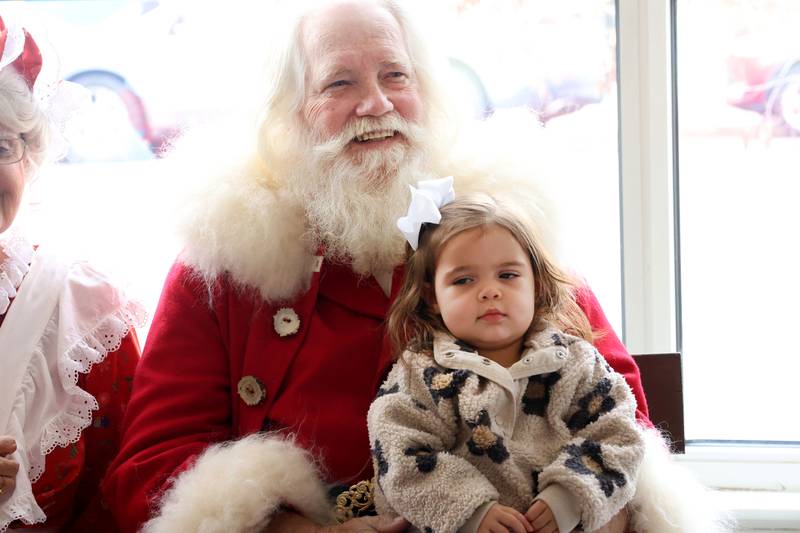 Santa Claus smiles as Amelia Landwehr sits on his lap during the annual Christmas Walk on Saturday, Nov. 22, 2025 at the Prouty Building Princeton.