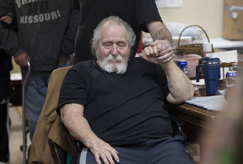 Clients at the PADS Shelter in Sterling join hands for a prayer and sharing good news Wednesday, Jan. 7, 2026, before dinner.