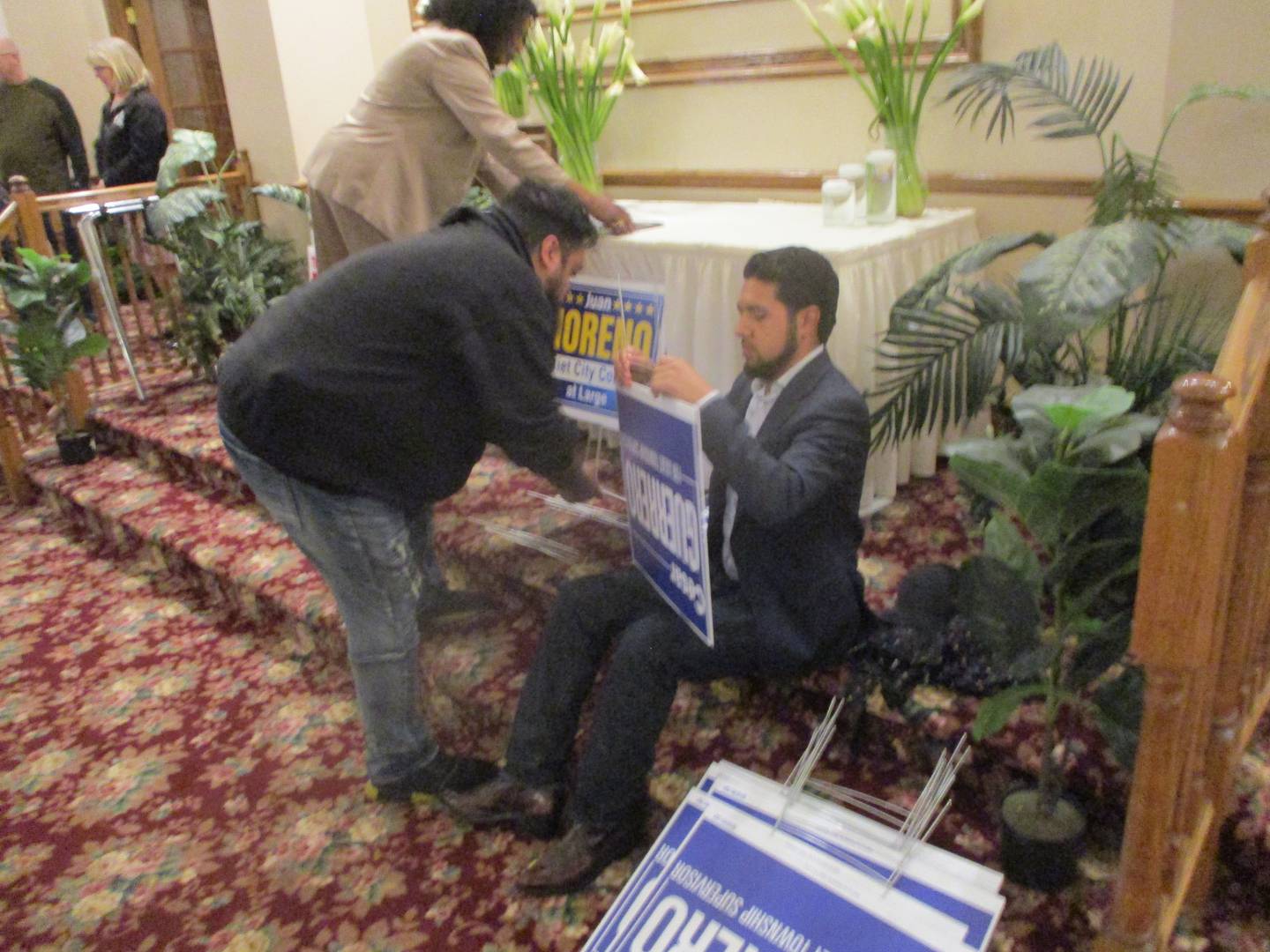 Joliet Township supervisor candidate Cesar Guerrero (right) and his brother, Jesus Guerrero, prepare campaign signs before the start of a candidates' forum at the Jacob Henry Mansion Estate in Joliet on Wednesday. March 19, 2025