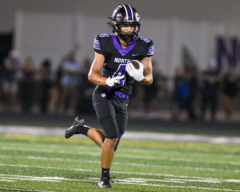 Downers Grove North's Caden Chiarelli (4) runs the ball before being brought down by Hinsdale Central defenders on Friday Sept. 12, 2025, held at Downers Grove North High School.