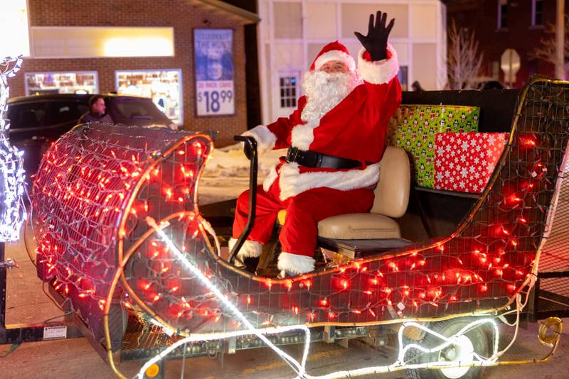Santa waves as he rides by on his sleigh float during the Christmas Parade on December 7, 2025 in Spring Valley.