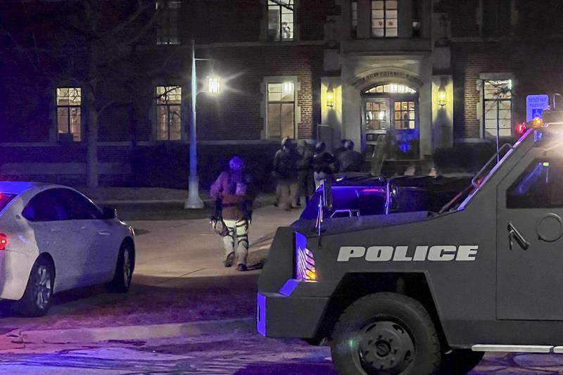 Armed police officers with weapons drawn rush into Phillips Hall on the campus of Michigan State University, in East Lansing, Mich., as authorities respond to reports of shootings, late Monday, Feb. 13, 2023. (Jakkar Aimery/Detroit News via AP)