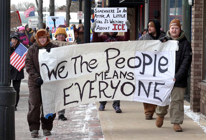 Protesters chant and carry signs as they march west down the sidewalk on Lincoln Highway in DeKalb Tuesday, Jan. 20, 2026, as part of a larger national Free America Walkout. The group is protesting what they perceive as an escalating fascist threat under President Donald Trump and his administration.
