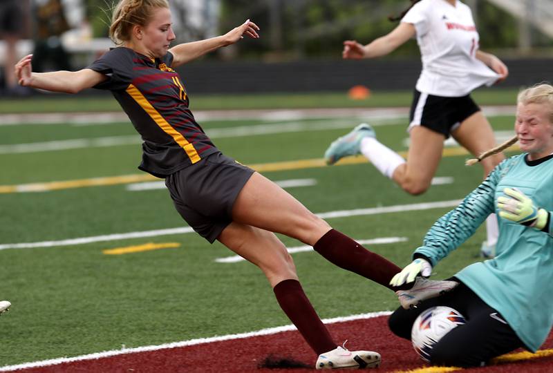 Richmond-Burton's Margaret Slove tries to kick the ball through Woodlands Academy goalkeeper Avery Drehkoff during a IHSA Division 1 Richmond-Burton Sectional semifinal soccer match Tuesday, May 16, 2023, at Richmond-Burton High School.