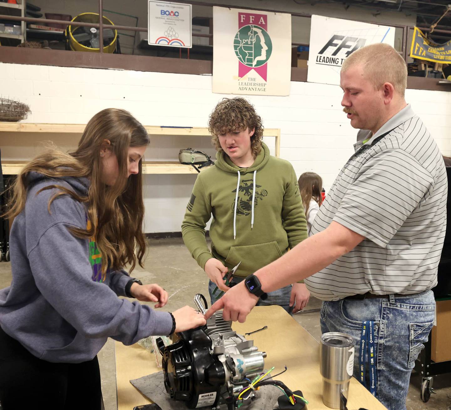 Sycamore High School agriculture teacher Christian Thurwanger works with sophomores Kaitlyn Lisafeld and Connor Wright during a small engines lab Monday, March 14, 2022, at the school. The lab is part of the agriculture program in the Career and Technical Education department at Sycamore High School.