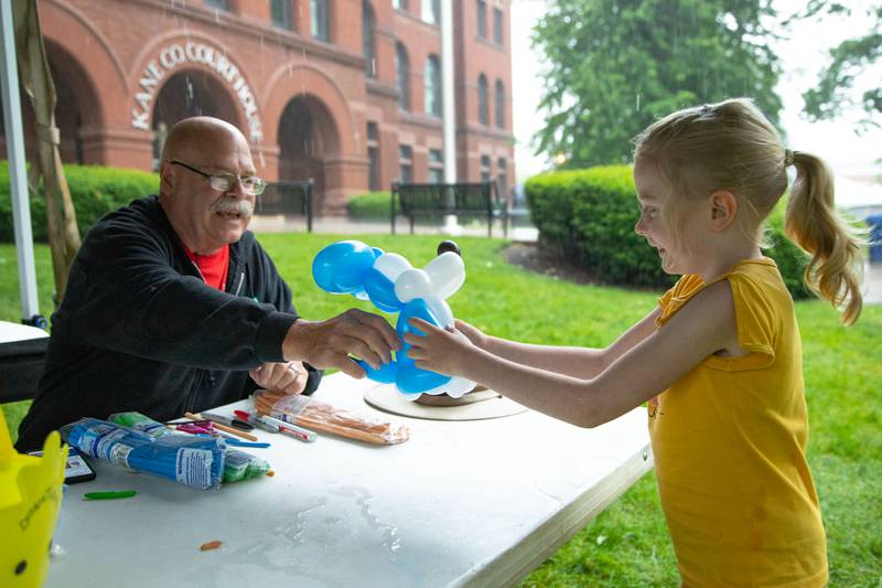 Sara Wistrand (6) of West Chicago receives a balloon animal from Mark Garvery, the owner of Papa Balloon and Friends, at Swedish Days on Saturday, June 25, 2022.