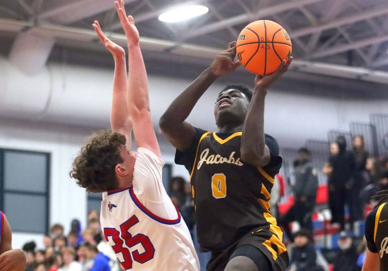 Jacobs’ Samson Averehi, right, drives against Dundee-Crown’s Hudson Reardon in varsity boys basketball on Friday, Dec. 12, 2025, at Dundee-Crown High School in Carpentersville.