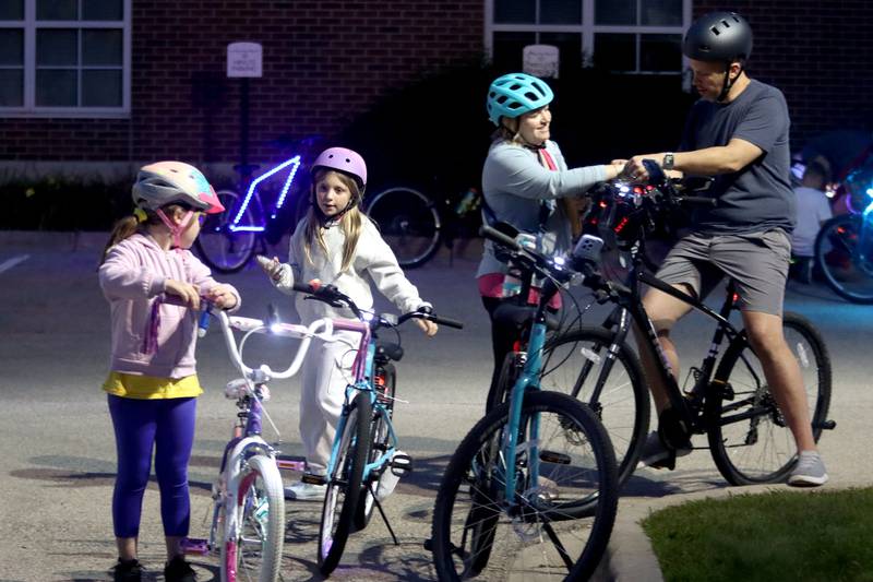 From left, Evelyn Postula,8, prepares with her cousin Ellie Postula, 8, along with Ellie’s parents Kristen and Andy Postula for the Raue Center for the Arts Night Owl Bike Ride in Crystal Lake on Saturday, August 2, 2025. All are from Crystal Lake.