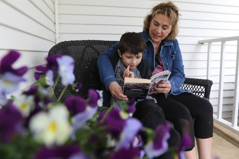 Chris Chirchirillo reads from a book borrowed from the little free library located at the end of her block with Jaxen Esparza, 8, on Saturday, April 24, 2021 in Lake in the Hills. Chirchirillo is one of 24 people to receive an outpatient robotic lung surgery at Northwestern Medicine and, four months later, is enjoying returning to normal activities.