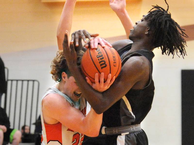 Sandwich's Austin Marks (22) and Kaneland's Freddy Hassan battle for a loose ball during a boys' basketball game at Sandwich High School on Friday, Jan. 13, 2023.