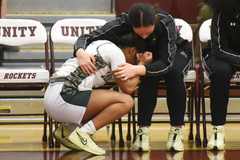 Bishop McNamara's Eliana Isom, left, is consoled by teammate Ella Langellier in the final moments of McNamara's 61-42 loss to Mt. Carmel in the IHSA Class 2A Tolono Unity Super-Sectional Monday, March 3, 2025.