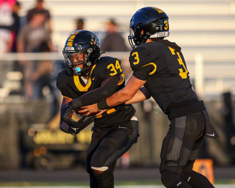 Joliet West's Tai’vaughn Johnson (34) takes the handoff from Juan Rico (3) during football game between Plainfield North at Joliet West.  Sept 15, 2023.