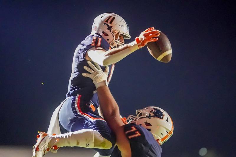 Oswego’s Teddy Manikas (11) is lifted into the air by Benjamin McCollum (77) after scoring a two point conversion against Plainfield North during a football game against Plainfield North at Oswego High School in September 2024.