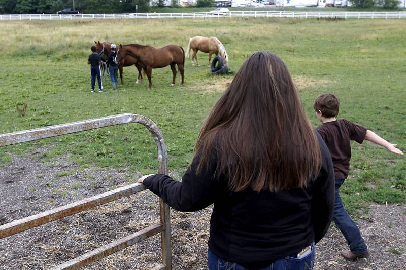 Brigette Birong watches as Richard Taylor-Terry, 11, and barn manager Melissa Capra, and her son, Joseph Birong, 6, head out to get retired Medieval Times horses Danta and Hunter from pasture before a riding lesson Friday July, 8, 2022, at the R Double J Ranch, 2800 Derby Lane, in McHenry. The R Double J Ranch recently got the contract to operate this equine facility from McHenry with the goal of making it more of a community-centric center and make learning about horses and riding open to all.