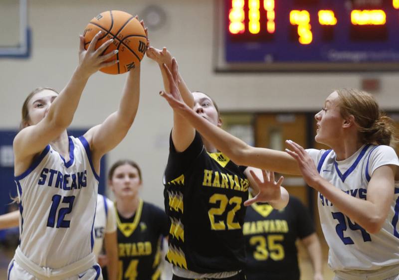 Woodstock's Hayden Williams grabs a rebound as she battles with Harvard's Summer Jones and Woodstock's Aiyana Fourdyce during a Kishwaukee River Conference girls basketball game on Monday Jan. 12, 2026, at Woodstock High School.