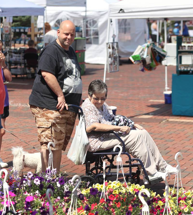 Kris Waramoski and his mom Gayle, from Channahon, look at some of the flowers at the Roden's Elegant Gardens booth Thursday, June 2, 2022, during the first DeKalb Farmers Market of the season at Van Buer Plaza in Downtown DeKalb.