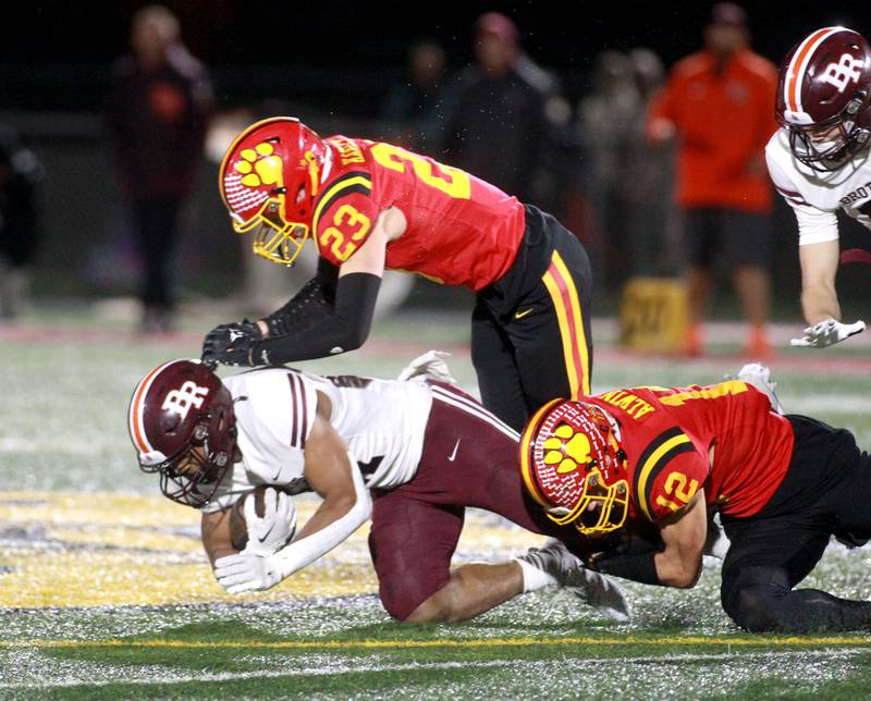 Batavia’s Luke Alwin (bottom right) and Josh Kahley (top) take down Brother Rice’s Randall Nauden during a Class 7A round 1 playoff game in Batavia on Friday, Oct. 27, 2023.