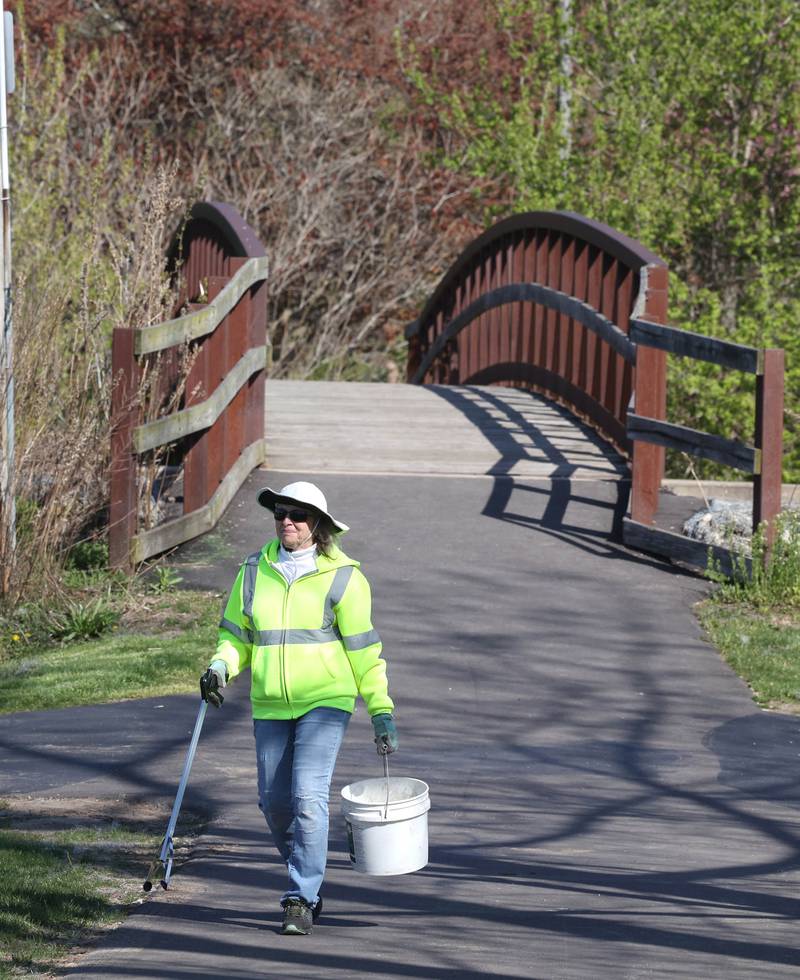 Inge Nicklaus, from DeKalb, looks for trash along the path Monday, April 22, 2024, during an Earth Day Clean Up event at Hopkins Park in DeKalb.