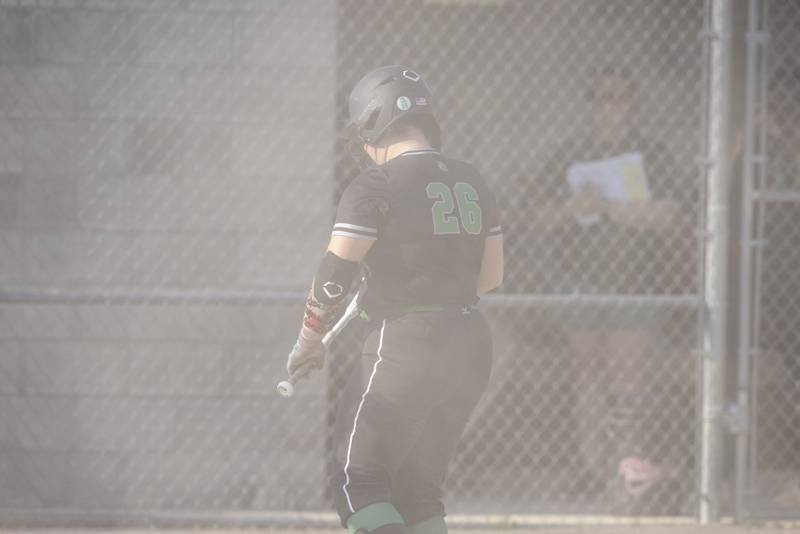 Dwight High School's Avery Scheuer shields herself from the blowing dust brought on by winds gusting over forty miles per hour during the Class 1A Sectional semifinal game at Woodland High School on May 21, 2024.