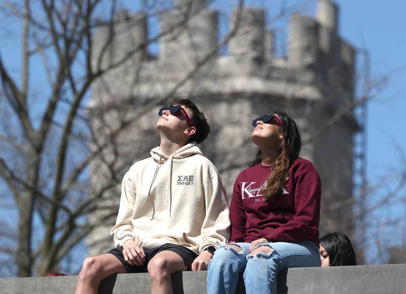 TJ McCann, a sophomore at Northern Illinois University from Carol Stream, and Jackie Tovar, a sophomore from Chicago, watch the eclipse Monday, April 8, 2024, from the back balcony of Founders Memorial Library at NIU. Attendees were treated to perfect weather to watch the rare celestial event.