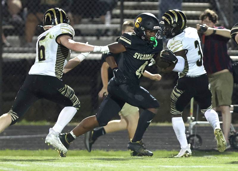 Sycamore's Tyler Curtis splits two Oak Forest defenders on a long run during their game Friday Sept. 2, 2022, at Sycamore High School.
