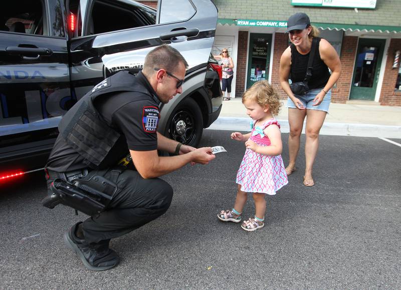Conrad Sek, police officer with the Wauconda Police Department, gives a sticker to Annabelle Middleton, 2, of Wauconda with her mother, Kara, standing close by during National Night Out on Main Street on Tuesday, August 1st in Wauconda.  
Photo by Candace H. Johnson for Shaw Local News Network.