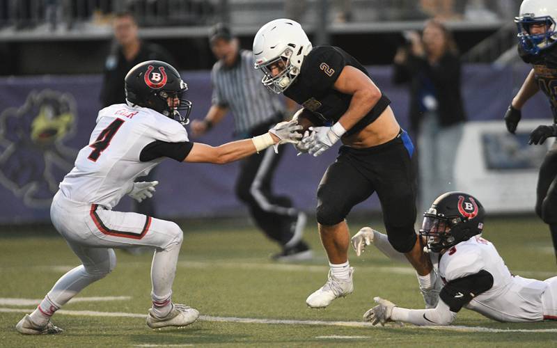 Warren’s Charley Thompson tries to escape Barrington’s Andrew Grosch at his feet and Jon Fier in front of him in a football game in Gurnee on Friday, August 26, 2022.