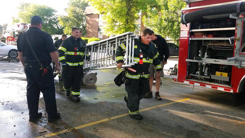 Firefighters bring a ladder back to the engine in the parking lot of Ridgebrook Apartments, 808 Ridge Road, DeKalb, after several residents had to be pulled from their apartments because fire had pinned them in.