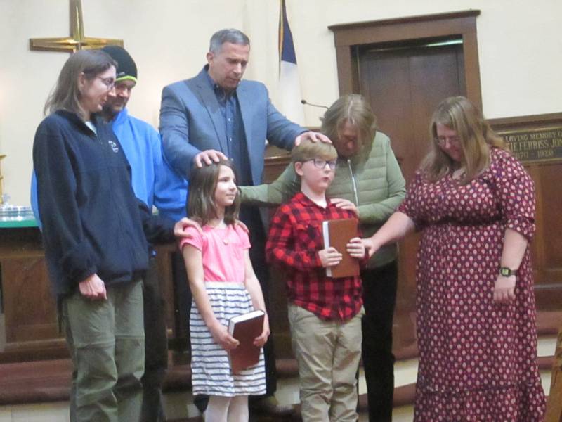 Pastor Stevan Saunders prays over the third grade children and their families as the children continue their Faith journey through their Bible they were presented.