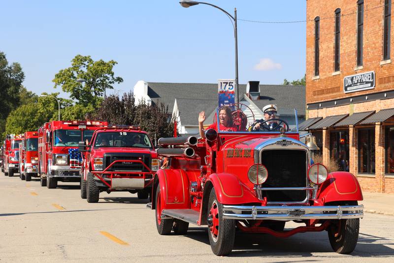 Parade participants wave to attendees as they drive a vintage St. Anne fire truck in the Grand Pumpkin Parade during the St. Anne Pumpkin Festival on Saturday, Oct. 4, 2025.