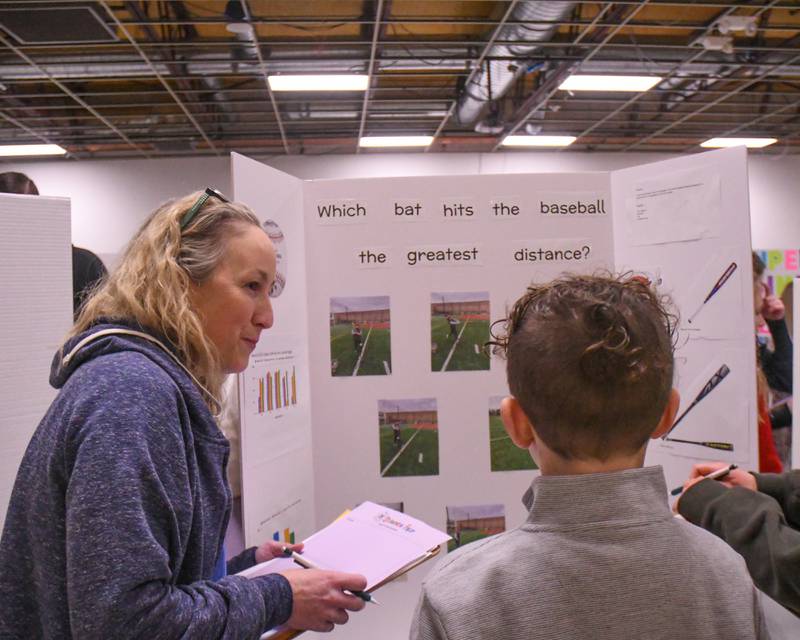 Terra Freder a judge during the Downers Grove District 58 science Fair on Saturday Jan. 25, 2025, talks with Drew Casey about his project where he tried different baseball bats to see what would make the ball go farther in distance held at O'Neill Middle School.