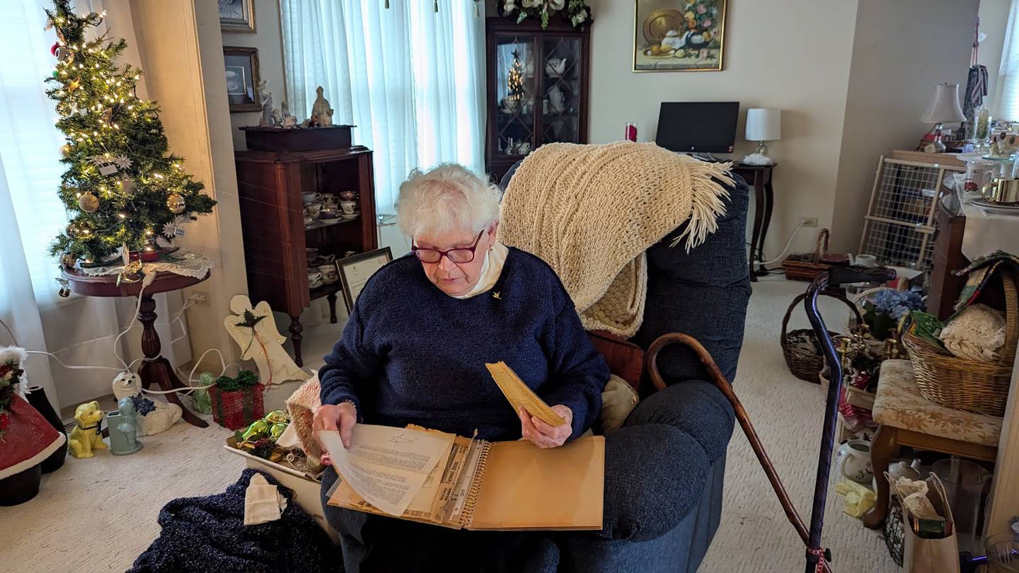Elvira Balog, 85, of Joliet, looks through memorabilia from the 25th anniversary of the former St. Stephen Catholic Church in Joliet on Monday, December 16, 2024. Balog watched original St. Stephen's Hungarian Chapel burn to ground on Dec. 31, 1948.