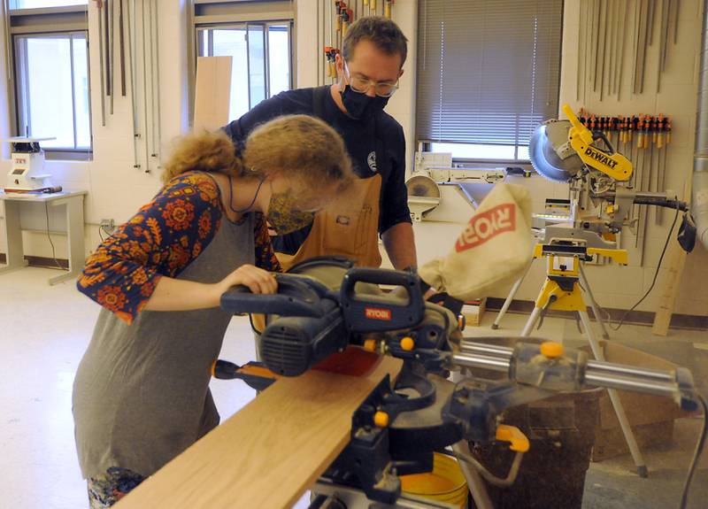 Teacher Brett Fankhauser watches as junior Reanna Garrett, 17, cuts a piece of wood as he teaches students in combined Woods 1 and Woods 2 class Wednesday, March 23, 2022, at Woodstock North High School. Fankhauser also teaches at Woodstock High School.