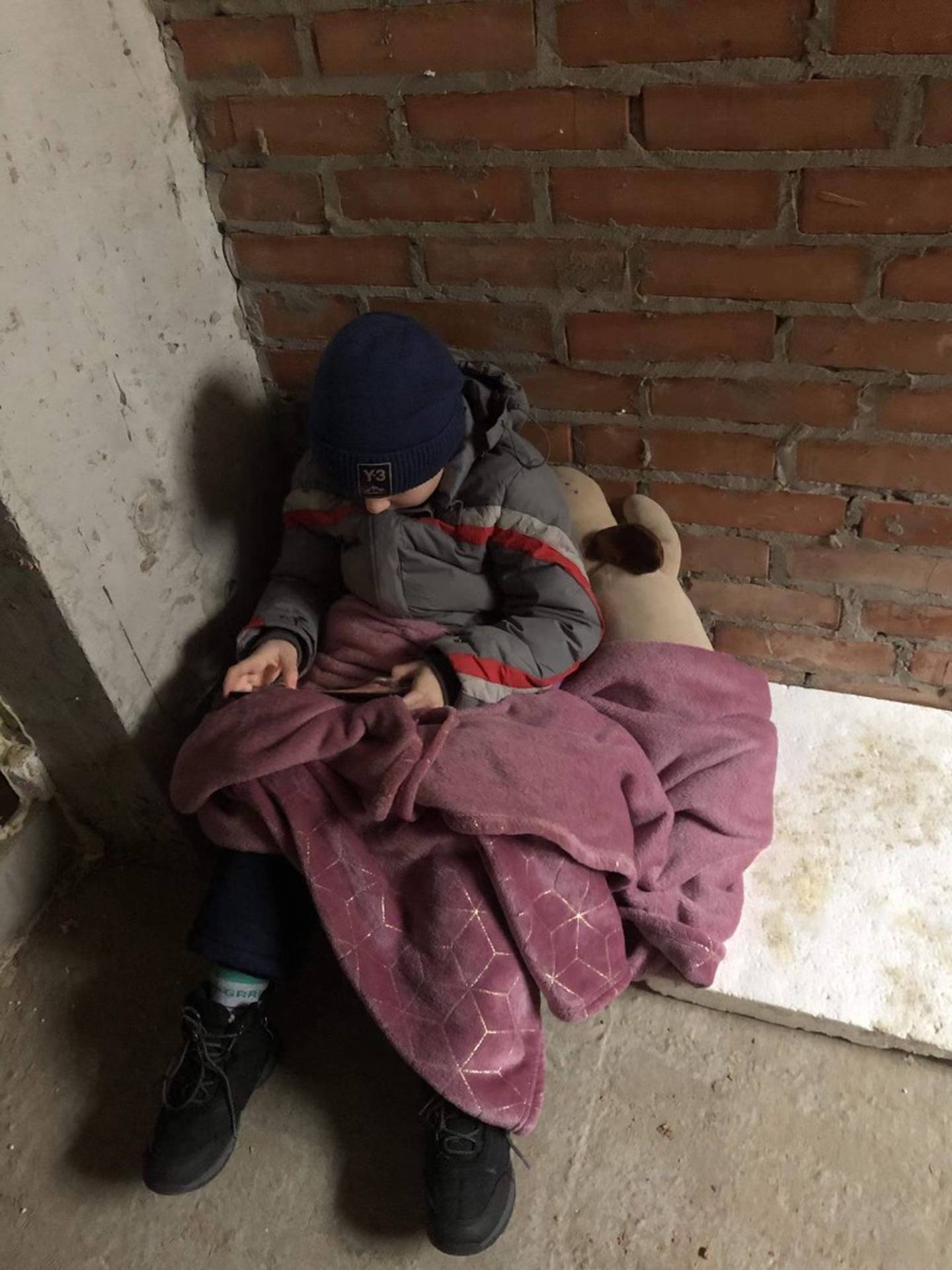 Vova Avramenko, 7, sits huddled with a blanket and a stuffed animal in a Kyiv bomb shelter during the Russian invasion of Ukraine on Feb. 24.