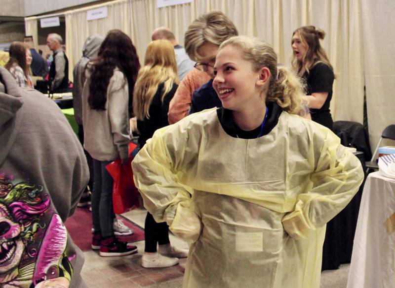 Nevaeh Scheffner, 13, tries on a medical smock while assisted by Rita Yahnke, a registered nurse at KSB Hospital in Dixon, on Friday, Oct. 14, at Sauk Valley Community College. More than 1,000 eighth-graders explored more than 50 career opportunities during Pathway Playground, an activity organized by Regional Office of Education 47.