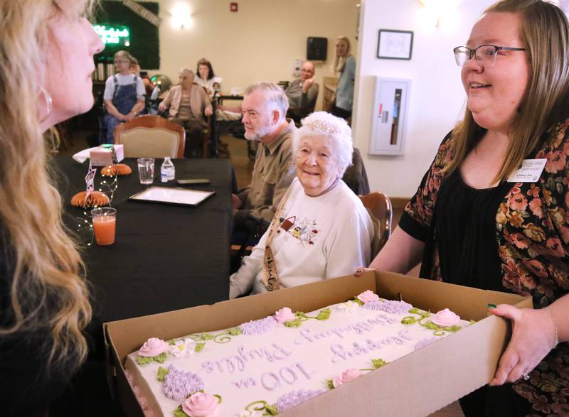 Heritage Woods of DeKalb resident Phyllis Fawcett, is presented with her cake during her surprise 100th birthday party Thursday, March 21, 2024, at Heritage Woods.