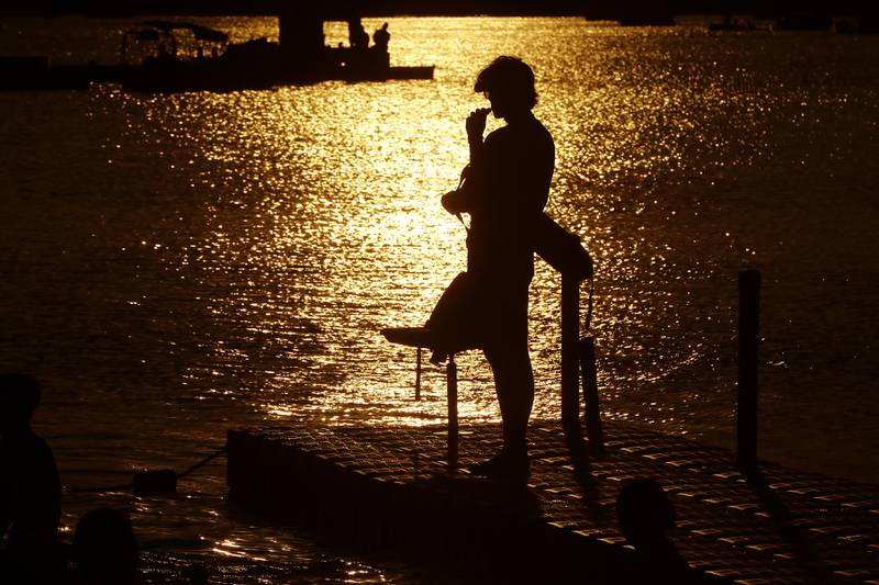 As the sun sets a lifeguard keeps his eyes on the water as people swim Sunday, July 2, 2023, at Crystal Lake’s Main Beach during Crystal Lake Annual Independence Day Celebration.