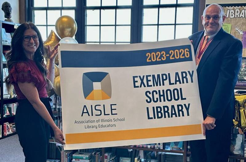 Ottawa High School librarian/media specialist Kelley Getzelman (left) and principal Pat Leonard display the banner marking the Exemplary School Library Award that OHS received from the Association of Illinois School Library Educators.