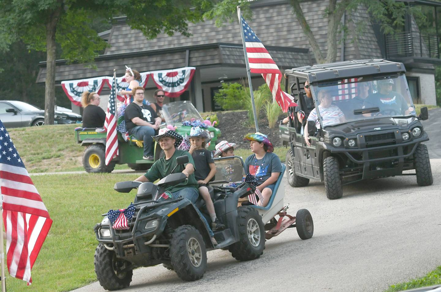 Weston Hughes, Jr., drives an ATV with Kolten Lowe as Jordan Lowe and Hank Hughes ride along in the 1968 Arctic Cat Cutter in the 2022 Grand Detour Golf Cart Parade.