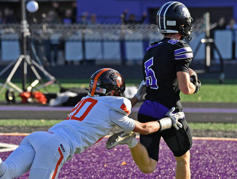 Downers Grove North’s Max Troha (5) reaches the end zone ahead a tackle attempt by Lincoln-Way West’s RJ Boye during a Class 7A quarterfinal game on November 15, 2025 at Downers Grove North High School in Downers Grove .