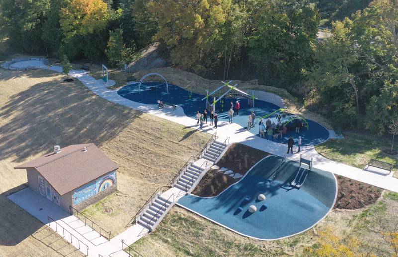 An aerial view of the new playground equipment during The City of Ottawa ribbon-cutting ceremony on Thursday, Oct. 17, 2024 at Allen Park in Ottawa. Commissioner Marla Pearson (center) cuts the ribbon on a 1.5 million dollar completion of a playground and other improvements to the park. The project was partially funded by a $506,000 IDNR Open Space Land Acquisition and Development grant. The new enhancements to Allen Park include accessible sidewalks leading to the upper plateau, featuring a modern playground and hillside play area with safe, poured-in-place surface for children of all abilities. The area also includes a shelter, bench swing with views of the Illinois River and a stone council ring for relaxation and community gatherings. 
A paved quarter-mile looped walking trail along the scenic banks of the Illinois River, two designated gaming areas, one with four bag toss stations and another with two chess-checkers tables and two ping-pong tables, all designed to promote social interaction and recreation. The sculptures will be repainted in the spring of 2025.