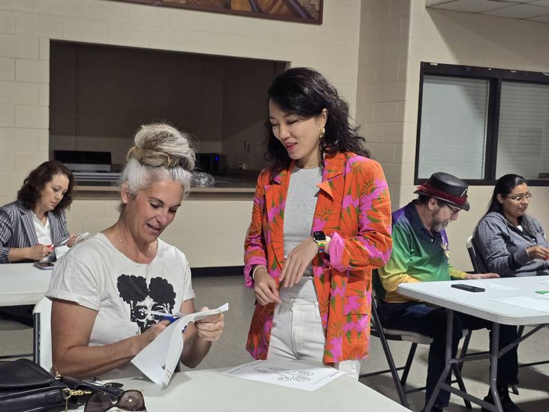 Michele Arana (left), owner of Internode Greenery and Home in downtown Joliet, experiments with the ancient art of paper cutting under Sijia Chen's gaze at a public art workshop on Saturday, Oct. 18, in Joliet. Chen is the Los Angeles-based multimedia artist for the Dome of Unity sculpture for Joliet’s $9 million city square.